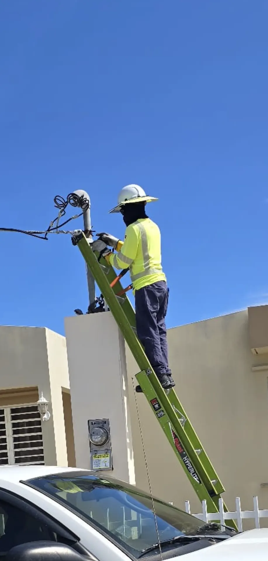 Electricista en escalera trabajando en la acometida y el contador de una residencia