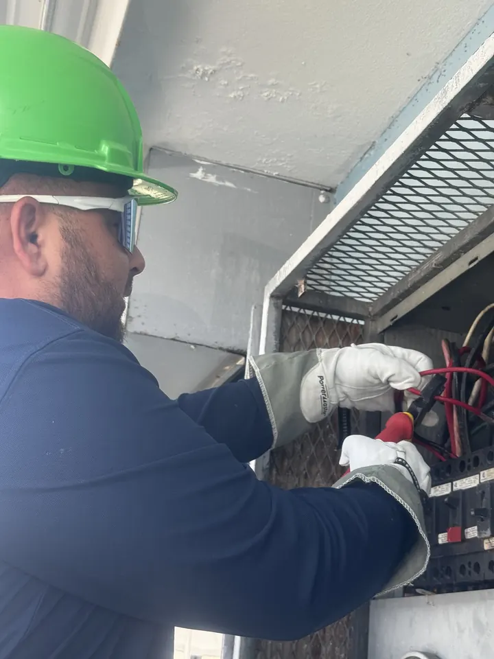 Electrician in a hard hat working on an electrical panel