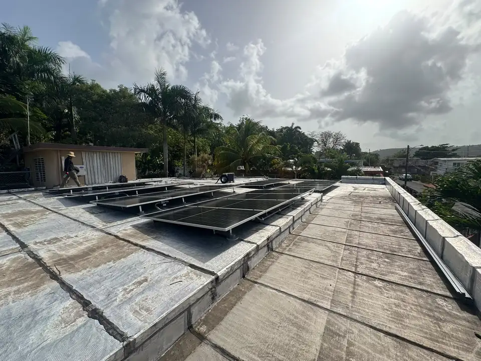 Technician walking beside newly mounted solar panels on a concrete roof